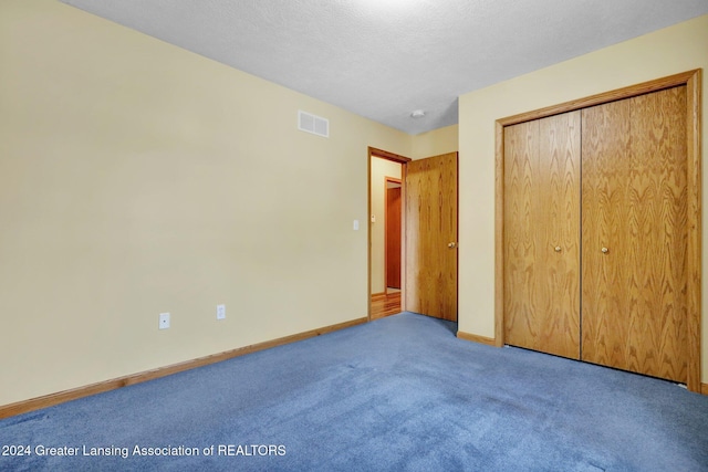 unfurnished bedroom featuring a textured ceiling, carpet floors, and a closet