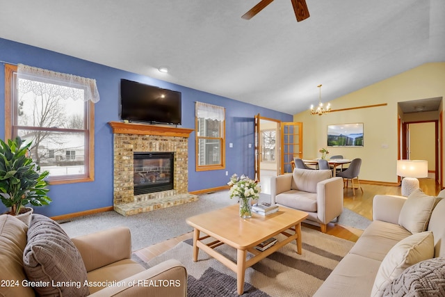 living room with a notable chandelier, lofted ceiling, a fireplace, and light hardwood / wood-style flooring