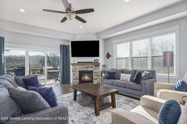 living room with ceiling fan, light hardwood / wood-style floors, and a stone fireplace