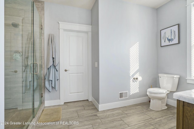 bathroom with an enclosed shower, vanity, and toilet