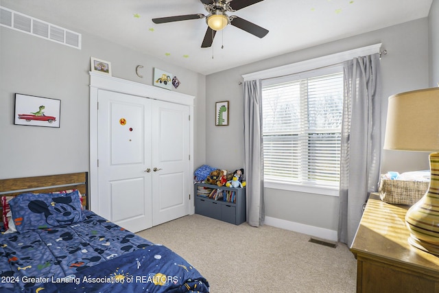 carpeted bedroom with ceiling fan and a closet