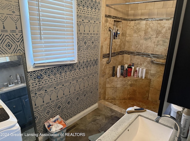 bathroom with a tile shower and vanity