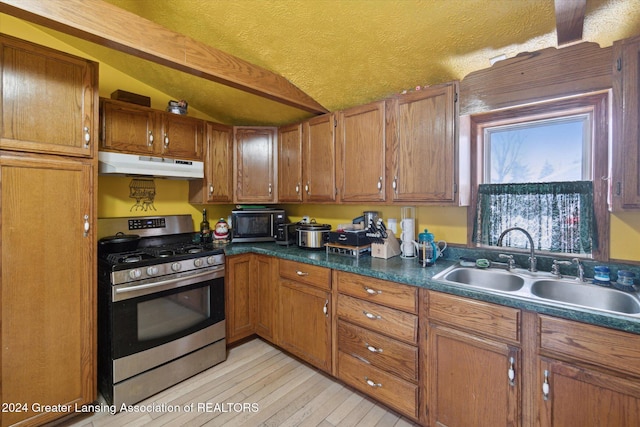 kitchen featuring sink, light hardwood / wood-style flooring, stainless steel gas range, and vaulted ceiling