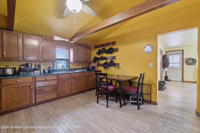 kitchen featuring sink, ceiling fan, light wood-type flooring, and vaulted ceiling with beams