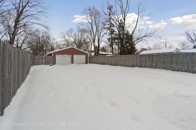 yard covered in snow featuring a garage and an outbuilding