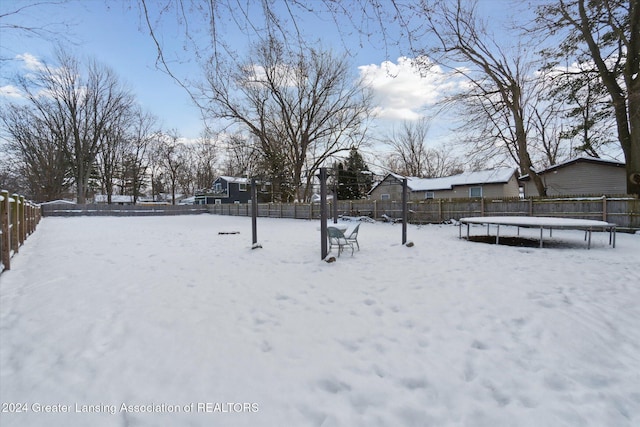 yard layered in snow with a trampoline