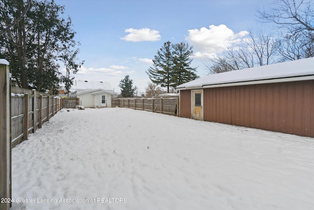 yard layered in snow featuring a storage shed