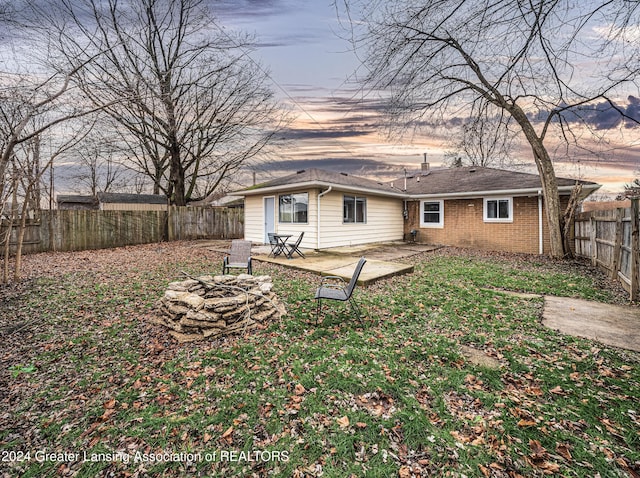 back house at dusk with a fire pit and a patio