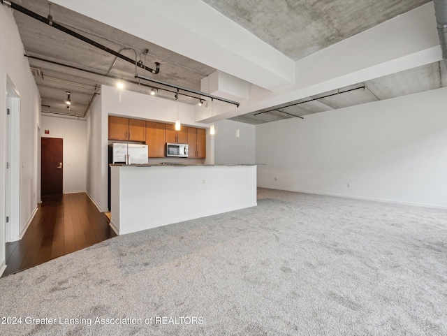 kitchen featuring kitchen peninsula, rail lighting, stainless steel appliances, and dark carpet