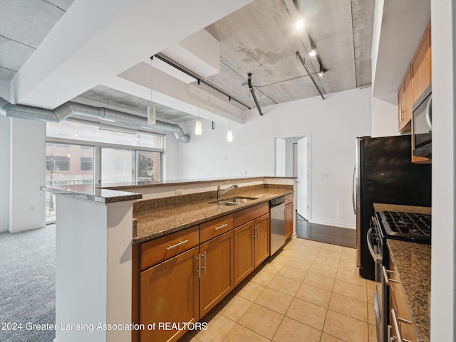 kitchen with sink, stainless steel appliances, dark stone counters, decorative light fixtures, and light tile patterned floors