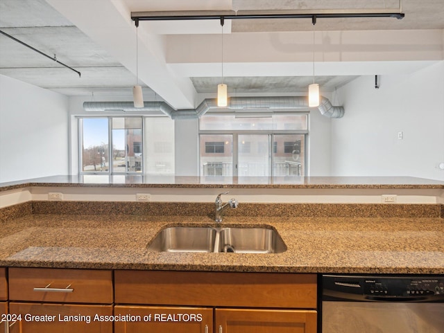 kitchen with light stone counters, decorative light fixtures, stainless steel dishwasher, and sink