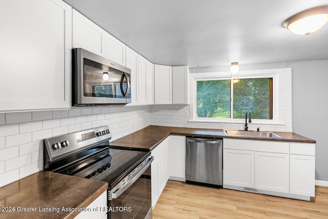 kitchen with white cabinets, sink, tasteful backsplash, light hardwood / wood-style floors, and stainless steel appliances