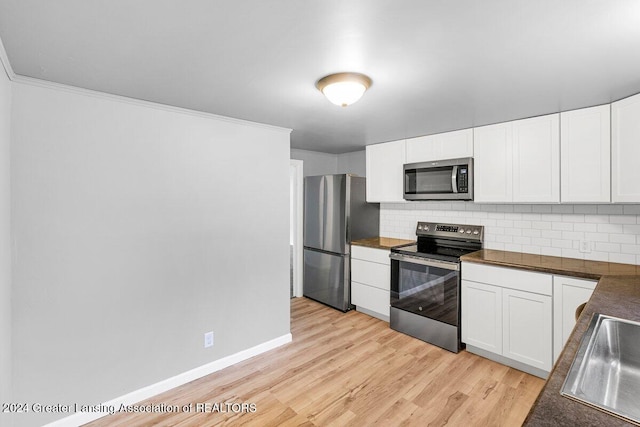 kitchen featuring decorative backsplash, stainless steel appliances, sink, light hardwood / wood-style flooring, and white cabinets