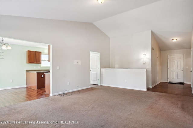 unfurnished living room with dark carpet, lofted ceiling, and a notable chandelier