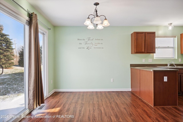 kitchen with a healthy amount of sunlight, hanging light fixtures, dark hardwood / wood-style floors, and a notable chandelier