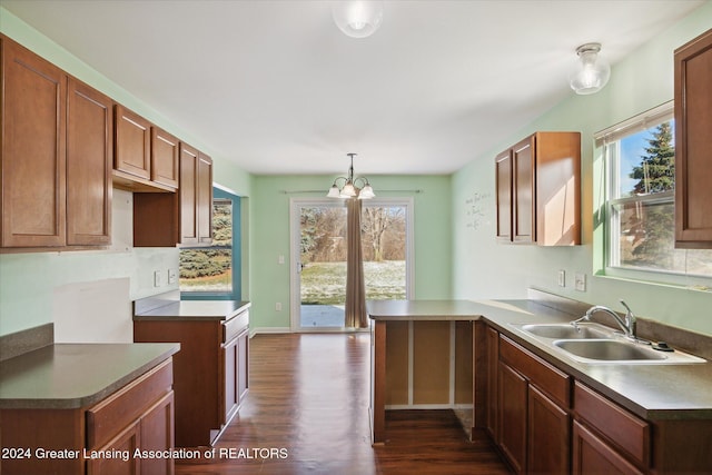 kitchen with dark wood-type flooring, an inviting chandelier, sink, decorative light fixtures, and kitchen peninsula