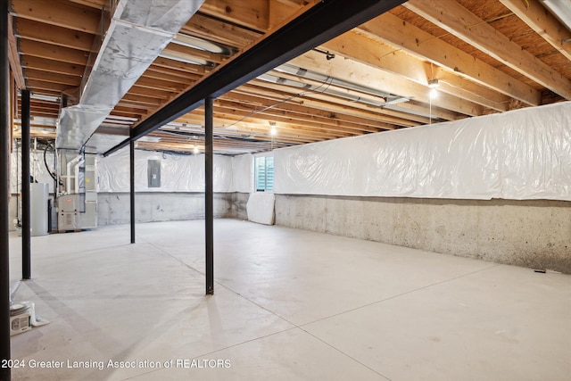 basement featuring electric panel and heating unit