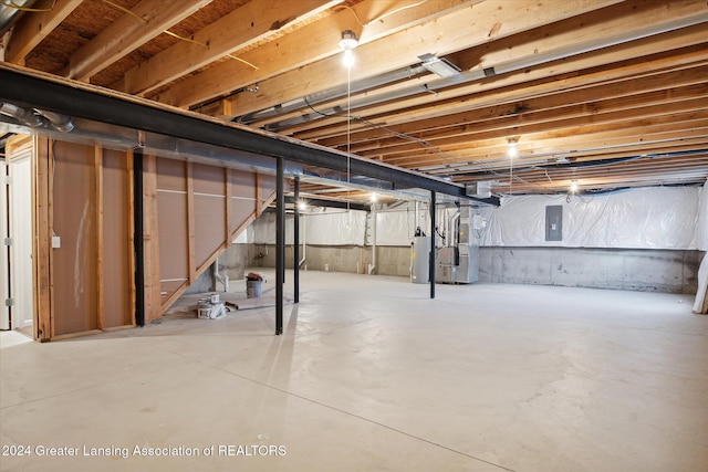 basement featuring electric panel, water heater, and heating unit