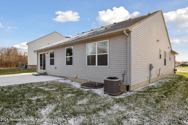 back of house featuring central air condition unit, a lawn, and a patio