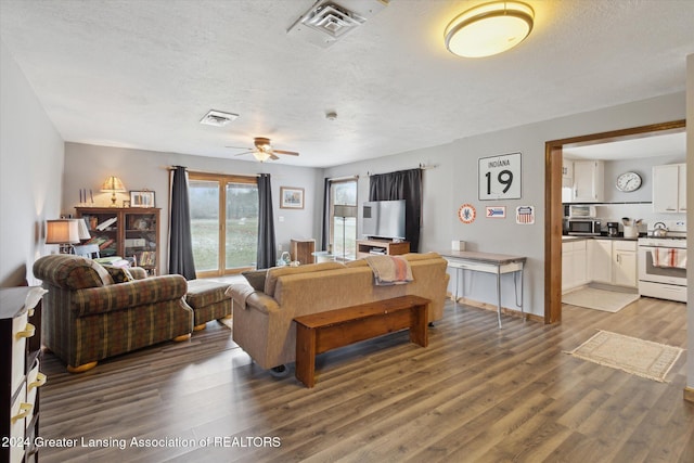 living room with ceiling fan, wood-type flooring, and a textured ceiling