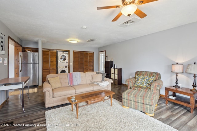 living room featuring ceiling fan, stacked washer and dryer, and dark wood-type flooring