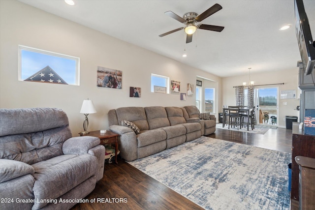 living room with ceiling fan with notable chandelier and dark wood-type flooring