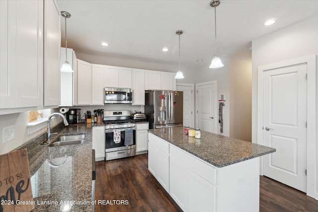 kitchen with appliances with stainless steel finishes, dark stone counters, sink, white cabinets, and a center island