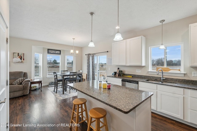 kitchen with white cabinetry, a center island, sink, dishwasher, and a breakfast bar