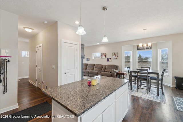 kitchen with a center island, hanging light fixtures, dark hardwood / wood-style floors, dark stone counters, and white cabinets