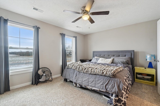 carpeted bedroom featuring a textured ceiling and ceiling fan