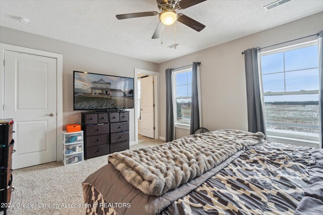 carpeted bedroom featuring ceiling fan and a textured ceiling