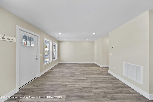 foyer entrance with visible vents, baseboards, and wood finished floors