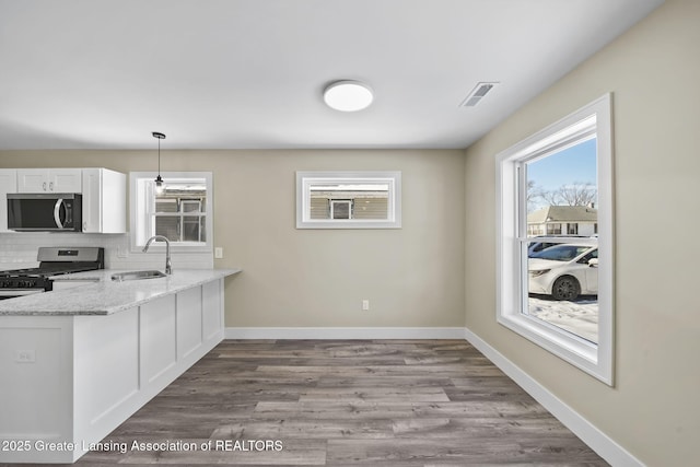 kitchen featuring baseboards, decorative backsplash, white cabinets, stainless steel appliances, and a sink