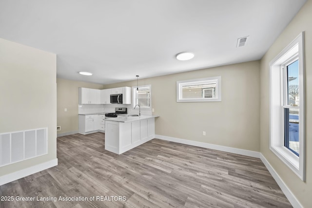 kitchen with visible vents, appliances with stainless steel finishes, a peninsula, and a sink