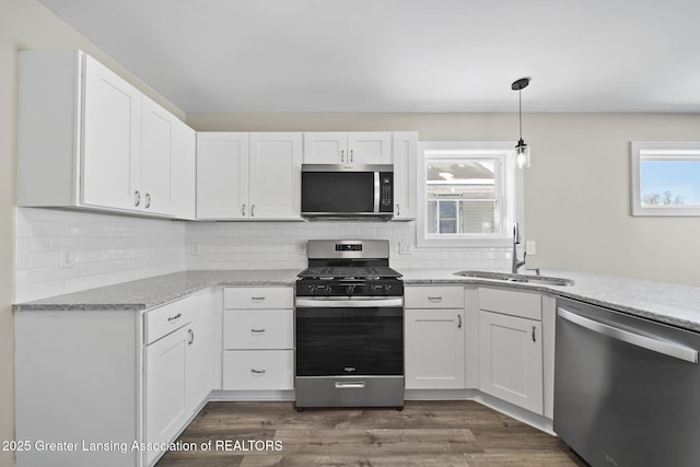 kitchen with decorative backsplash, dark wood-style floors, white cabinets, stainless steel appliances, and a sink