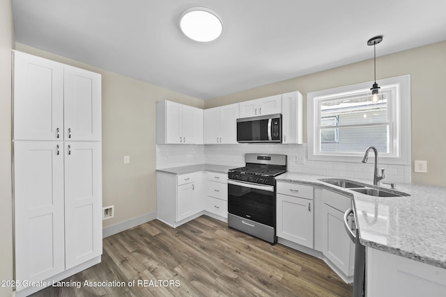 kitchen featuring light stone countertops, tasteful backsplash, appliances with stainless steel finishes, and a sink