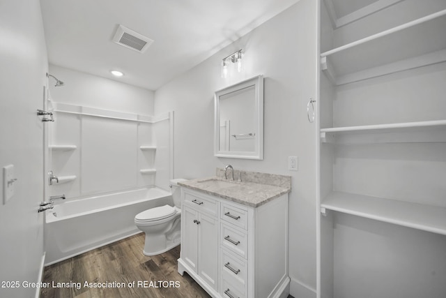 bathroom with visible vents, toilet, wood finished floors, vanity, and shower / bathtub combination