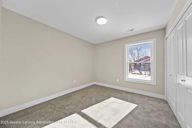 unfurnished bedroom featuring a closet, baseboards, carpet floors, and visible vents