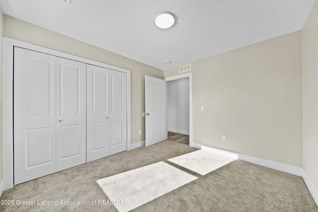 unfurnished bedroom with carpet, visible vents, a closet, and baseboards