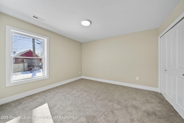 unfurnished bedroom featuring carpet, visible vents, a closet, and baseboards