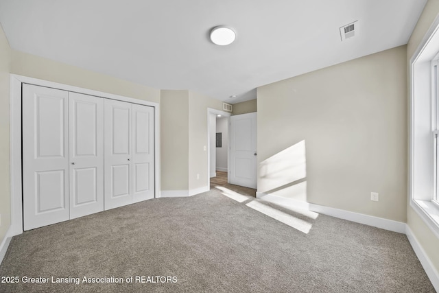 unfurnished bedroom featuring baseboards, a closet, carpet floors, and visible vents