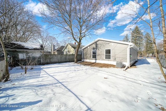 snow covered back of property featuring cooling unit and fence