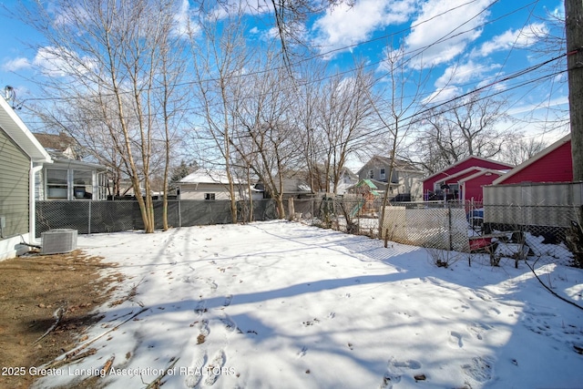 yard covered in snow featuring a residential view, central AC unit, and fence private yard