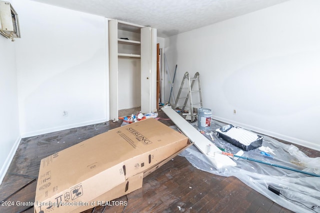 bedroom with a textured ceiling, dark hardwood / wood-style floors, and a closet