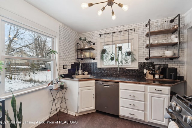 kitchen featuring decorative backsplash, stainless steel appliances, sink, a notable chandelier, and white cabinetry