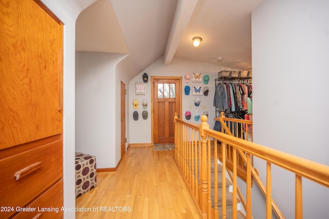 corridor with lofted ceiling with beams and light hardwood / wood-style floors