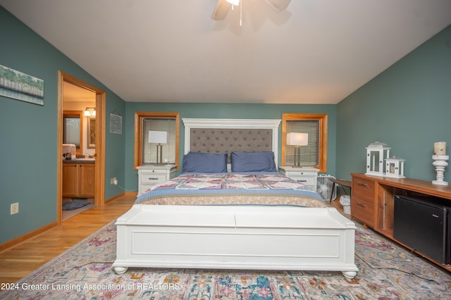 bedroom with light wood-type flooring, ceiling fan, lofted ceiling, and connected bathroom