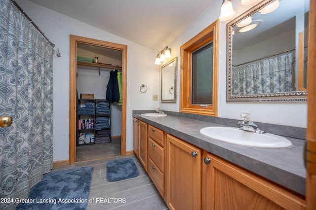 bathroom featuring tile patterned floors, vanity, and vaulted ceiling