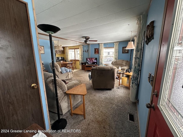 living room featuring a textured ceiling, carpet floors, and ceiling fan