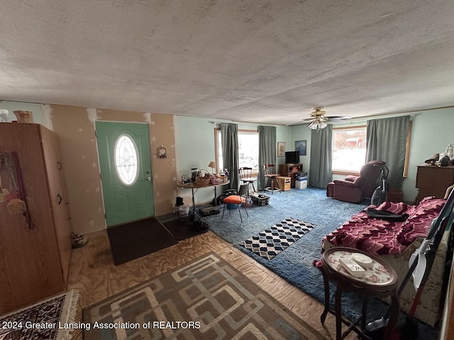 interior space with ceiling fan, a textured ceiling, and a wealth of natural light